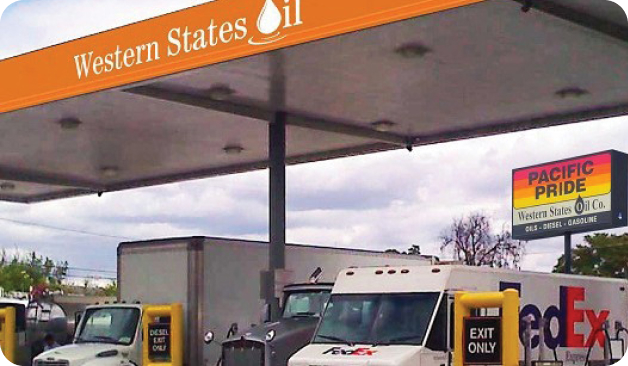 FedEx trucks parked under a Western States Oil gas station canopy, with a Pacific Pride sign visible in the background.